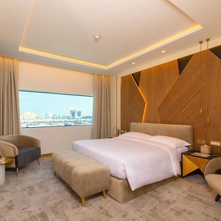 Steigenberger Hotel Doha Exteriör bild The photo showcases a modern hotel room with a stylish and contemporary design. It features a spacious layout with a large bed placed in the center, dressed in white linens. Behind the bed is an accent wall made of wood, which adds warmth and texture