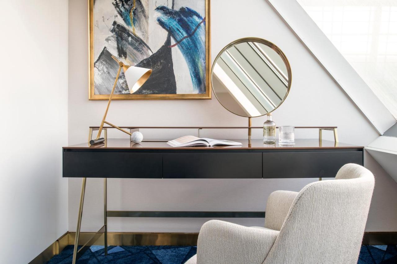 Steigenberger Hotel Doha Exteriör bild The photo showcases a stylish workspace setup. It features a sleek black desk with a minimalist design, supported by thin golden legs. Above the desk hangs a large, abstract painting with blue and black tones, adding an artistic touch to the space. O