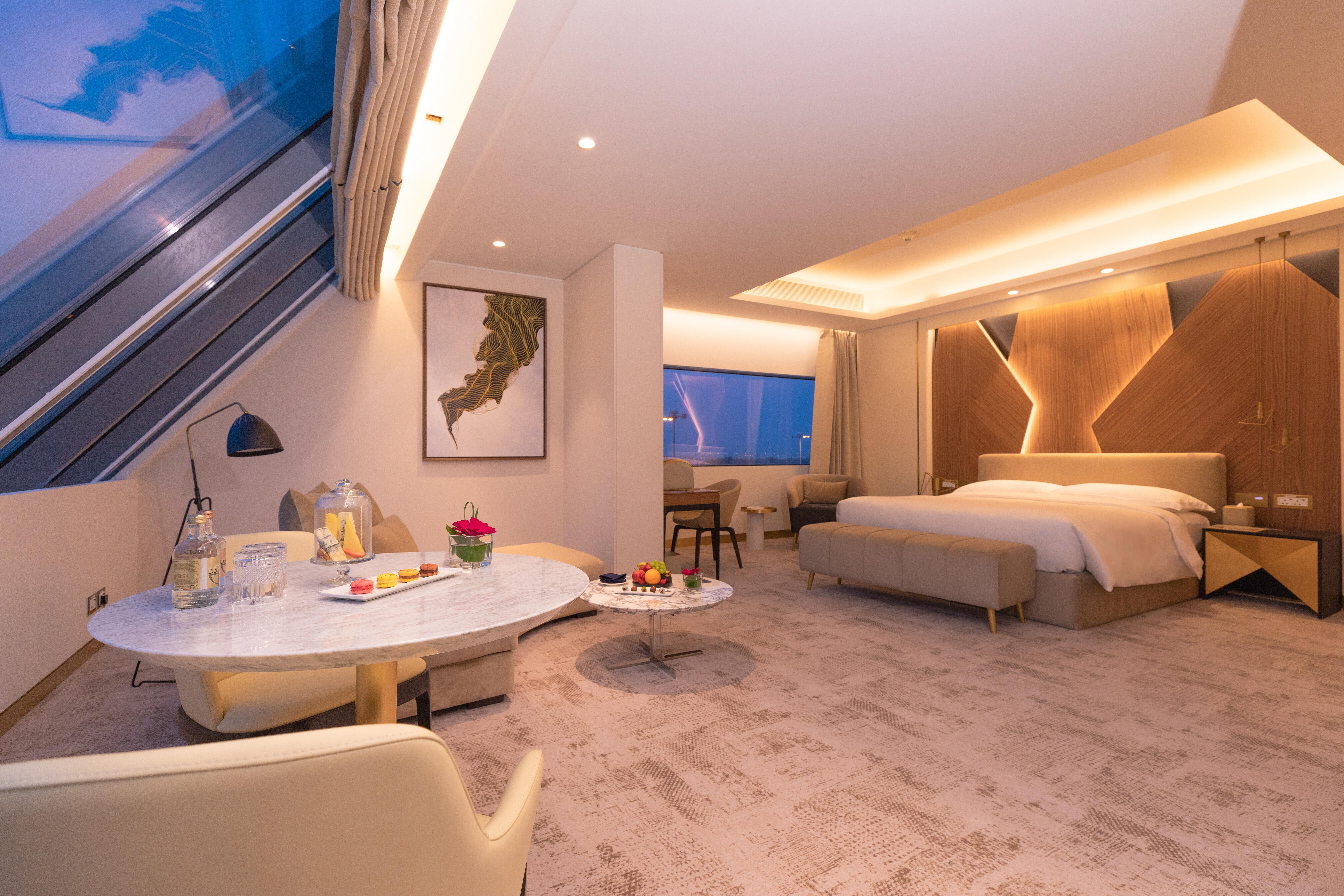 Steigenberger Hotel Doha Exteriör bild The photo shows a modern hotel room featuring a spacious layout with minimalist decor. The room includes a large bed with elegant bedding, soft lighting, and contemporary furnishings. A seating area with a small table and chairs is present, along wit