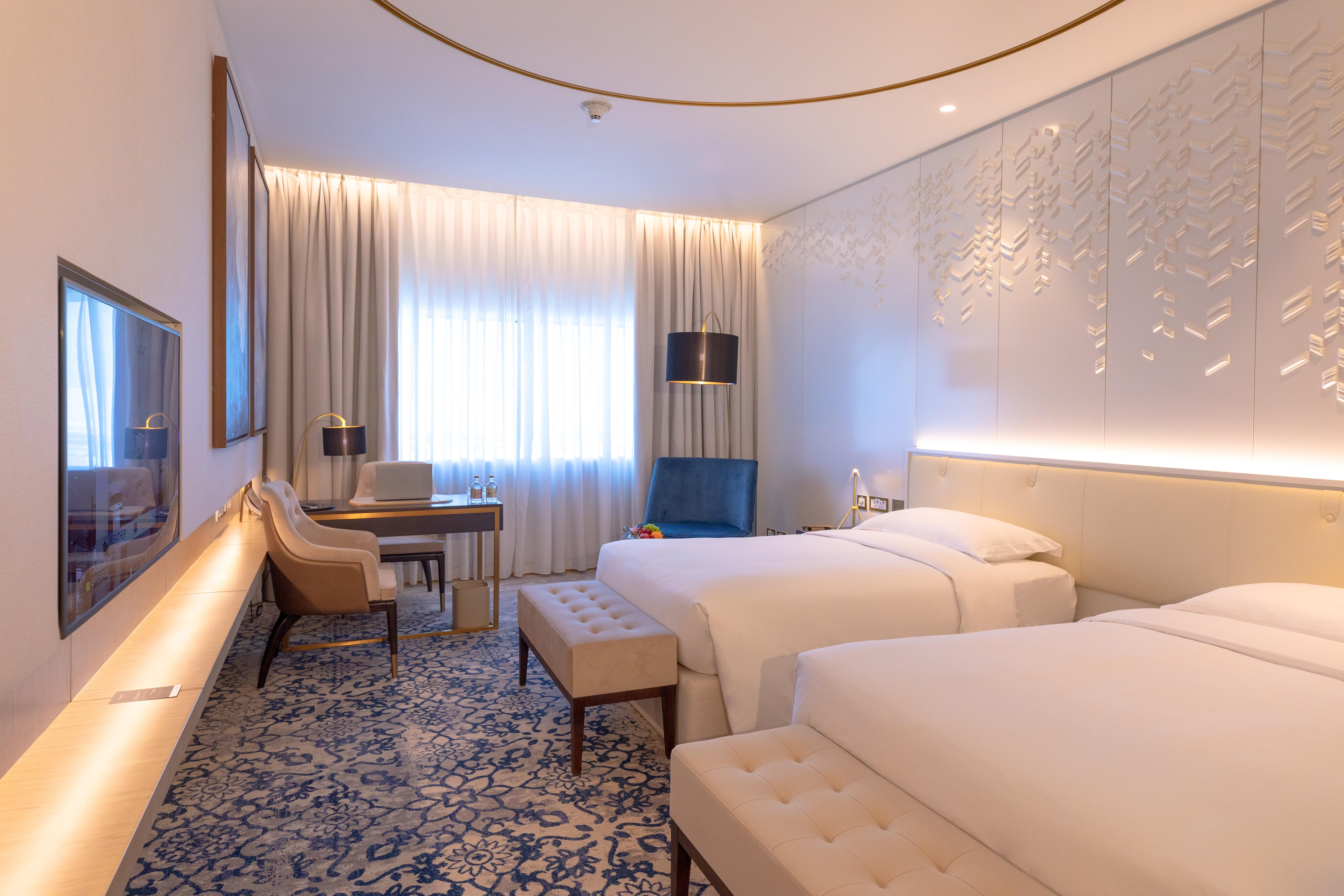 Steigenberger Hotel Doha Exteriör bild The photo shows a modern hotel room with two single beds placed beside each other. The room features a contemporary design with light-colored walls and stylish decor. There is a large window dressed with sheer curtains, allowing natural light to fill