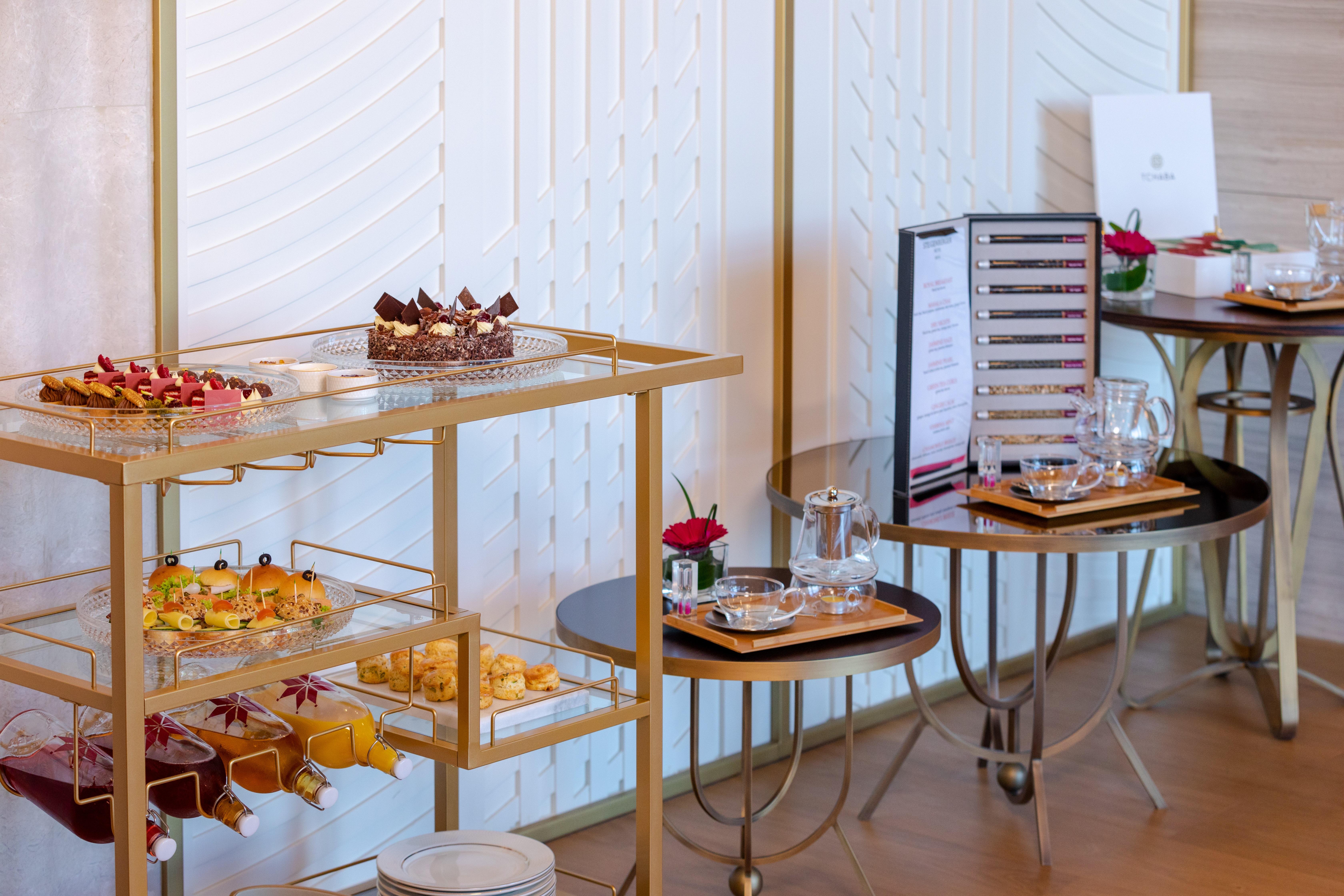 Steigenberger Hotel Doha Exteriör bild The photo shows a beautifully arranged buffet table featuring a variety of desserts and snacks. There is a gold cart displaying an assortment of pastries and small treats, including colorful hors d'oeuvres and mini desserts, likely for a high-end eve