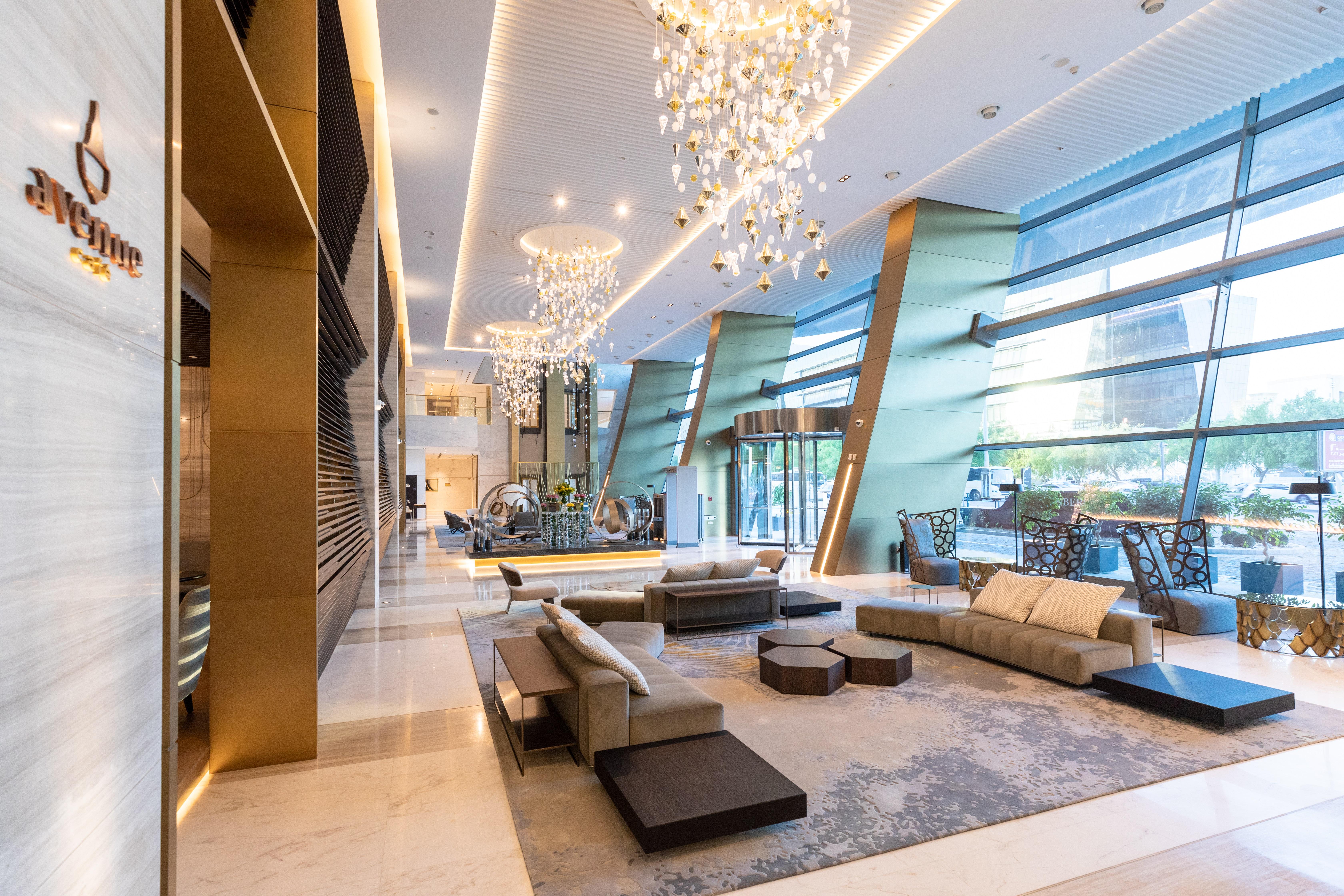 Steigenberger Hotel Doha Exteriör bild The photo shows a modern and elegant hotel lobby. It features stylish furniture, including sofas and coffee tables, arranged in a welcoming layout. The space is well-lit by several large chandeliers hanging from the ceiling, adding a touch of luxury.