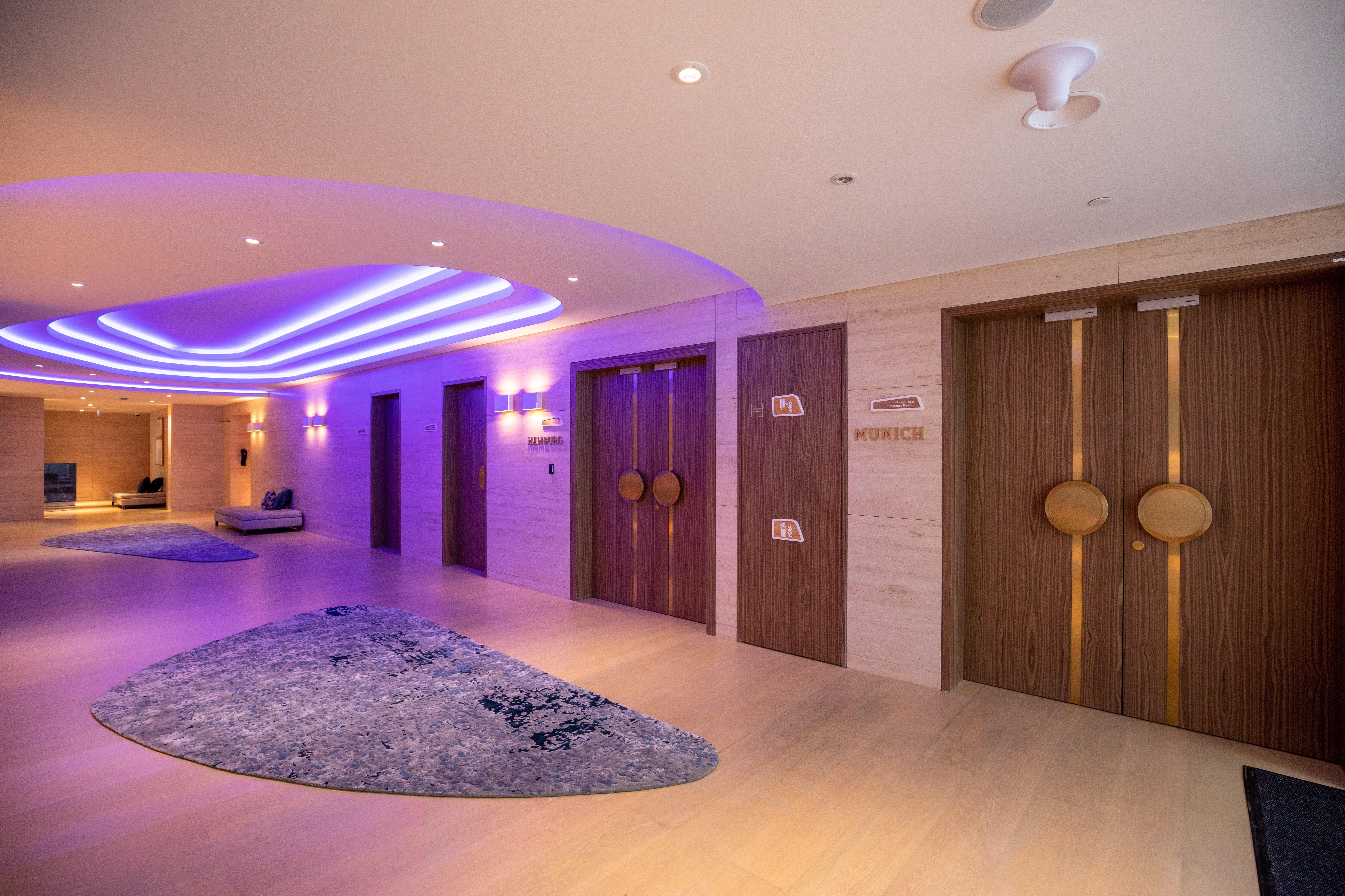 Steigenberger Hotel Doha Exteriör bild The photo shows a modern interior space, likely a hotel or spa. There are two prominent wooden doors with circular handles, which could be entrances to different facilities. The walls are adorned with subtle lighting, creating a warm and inviting amb
