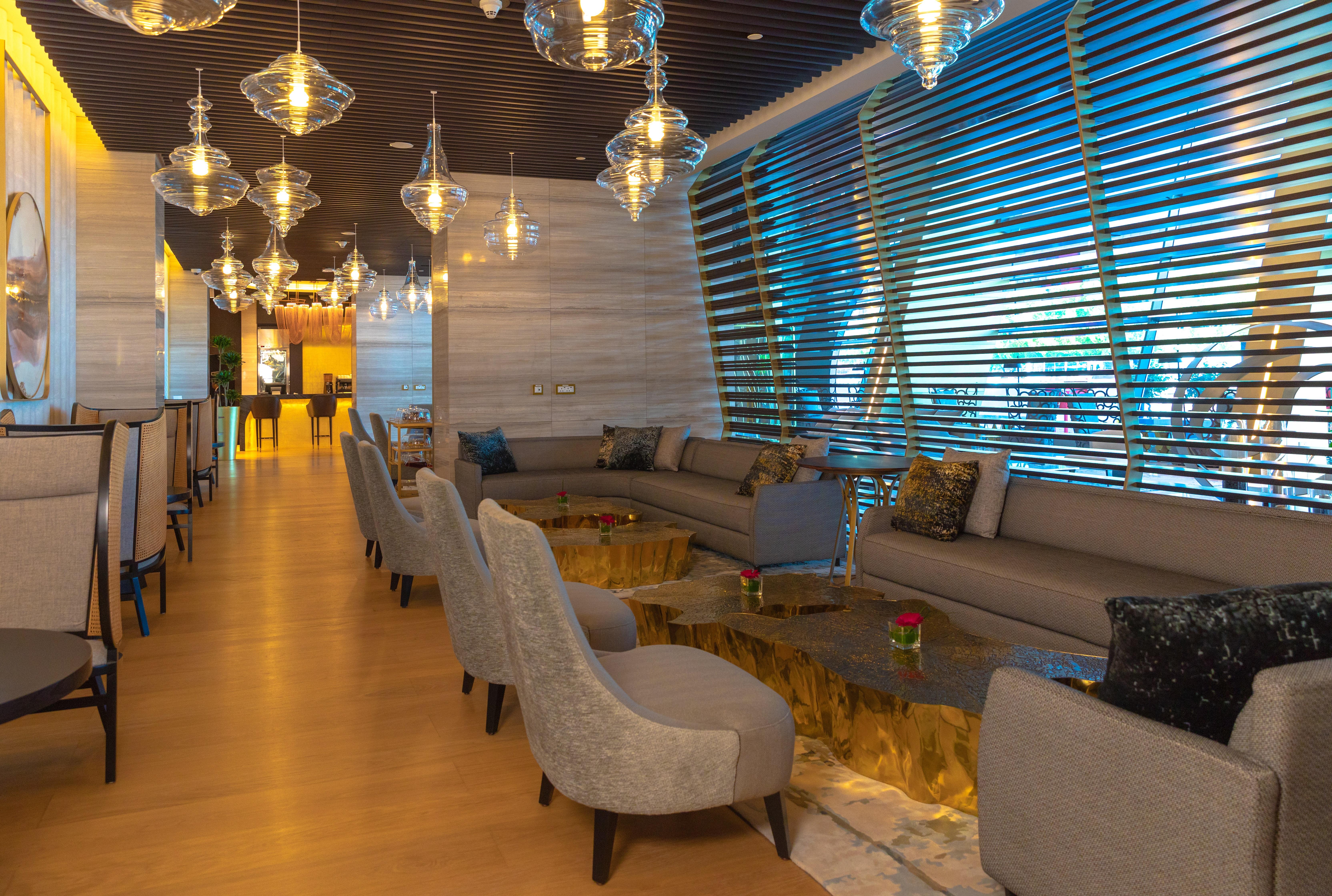 Steigenberger Hotel Doha Exteriör bild The photo depicts a modern and stylish lounge area. It features a spacious layout with comfortable seating arrangements, including beige sofas and stylish chairs. The tables have a unique design, with a gold-colored base. Ambient lighting is provided