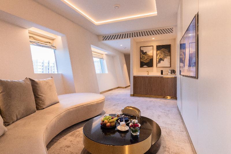 Steigenberger Hotel Doha Exteriör bild The photo shows a modern and stylish interior space, likely a lounge or a living area. It features a curved sofa in a light color, providing a comfortable seating arrangement. In the center, there is a round coffee table adorned with a selection of f